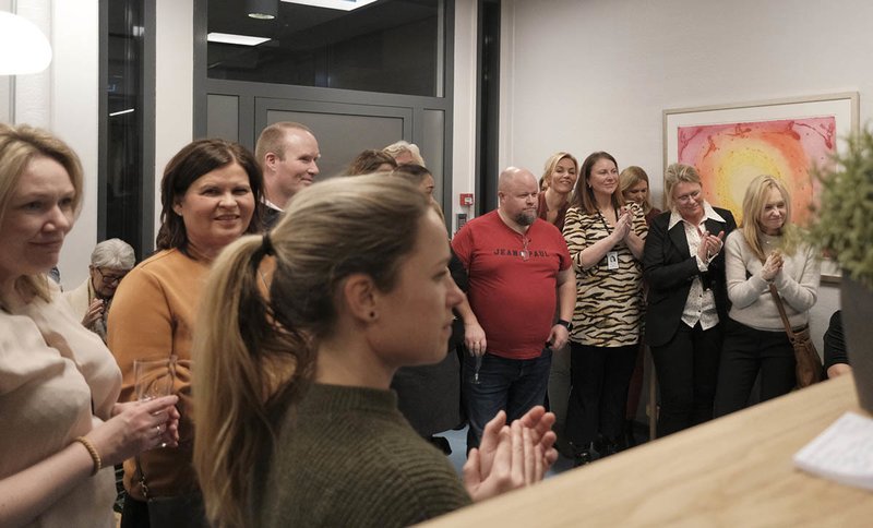 En gruppe mennesker står inne i lokalene til Spiren Fertilitetsklinikk og applauderer